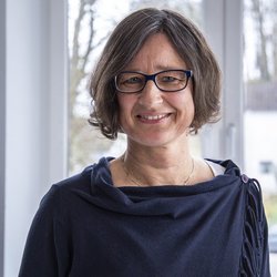 lächelnde Frau mit Brille im schwarzen Oberteil