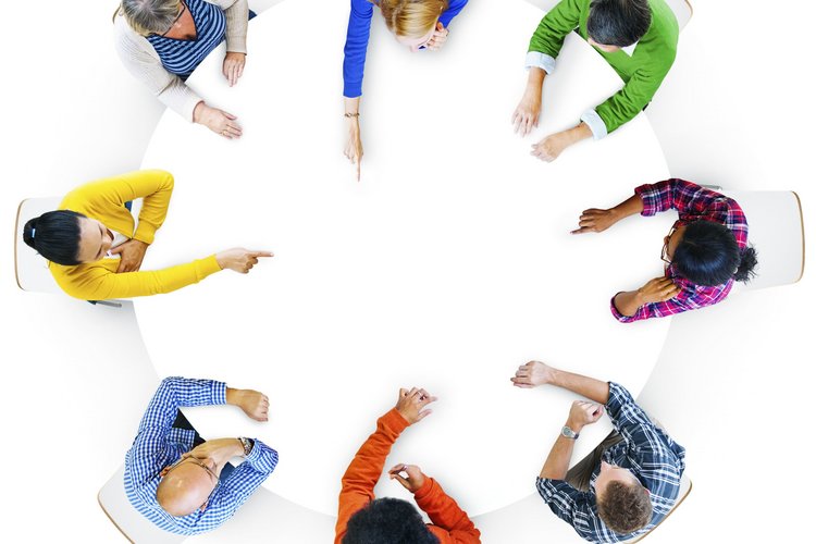 Menschen in bunten Oberteilen am Tisch aus Vogelperspektive