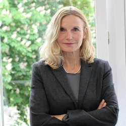 lächelnde blonde Frau im schwarzen Blaser