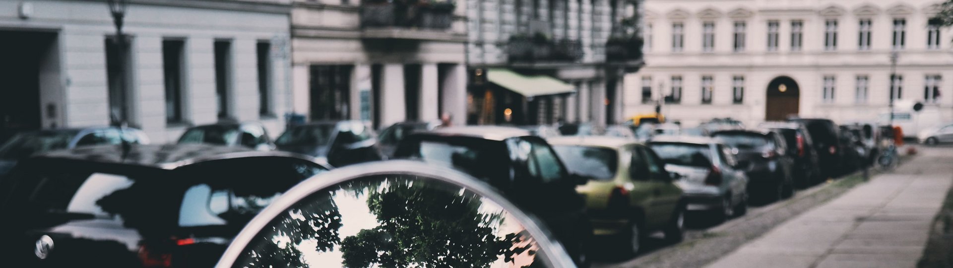 Spiegelung im Seitenspiegel mit parkenden Autos im Hintergrund