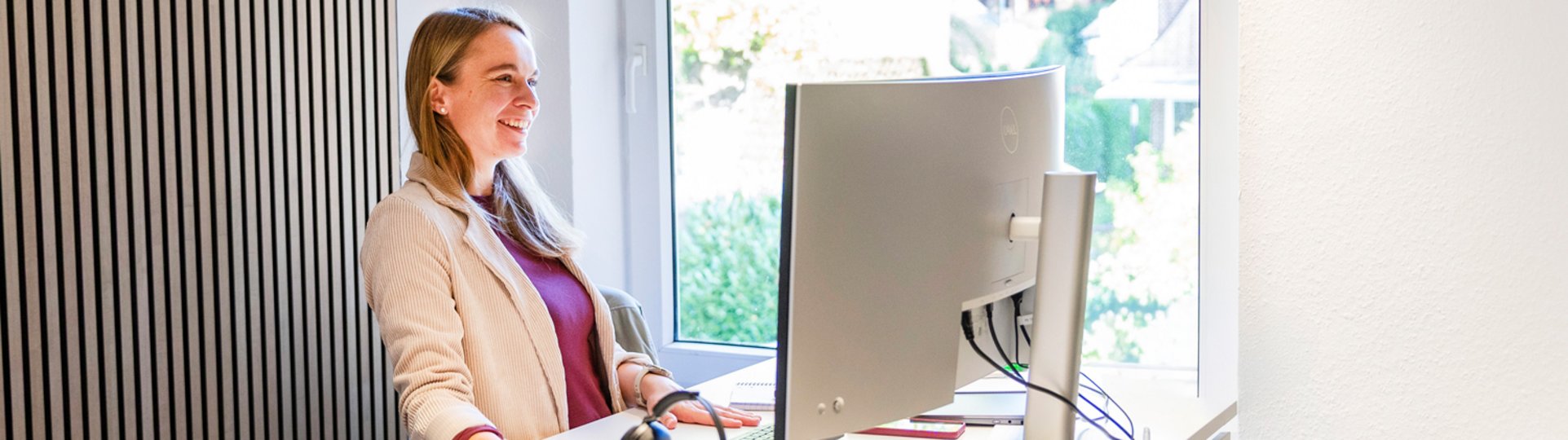 blonde Frau lächelnd am Arbeitsplatz
