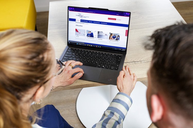 2 Mitarbeiter schauen sich die Website auf einem Laptop an