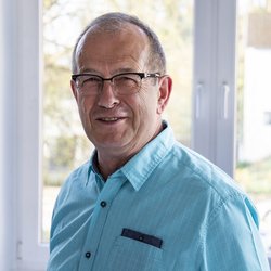 lächelnder Mann mit Brille im blauen Hemd