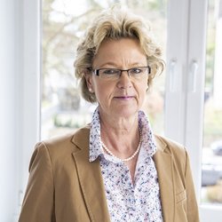 blonde Frau mit Brille im beigen Blaser